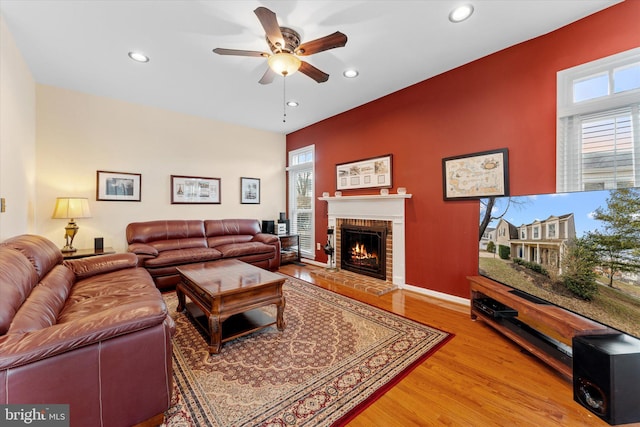 living room featuring hardwood / wood-style flooring, ceiling fan, and a fireplace