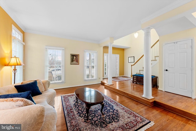 living room featuring decorative columns, wood-type flooring, and ornamental molding