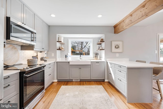 kitchen featuring electric stove, sink, a breakfast bar, light hardwood / wood-style floors, and kitchen peninsula