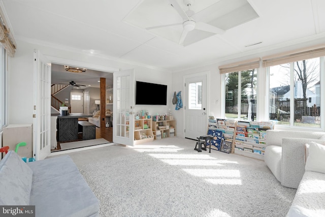 carpeted living room with a wealth of natural light, ornamental molding, and french doors