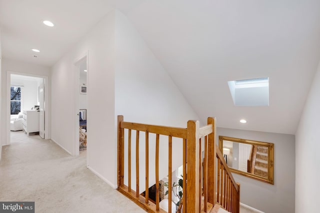 hallway with vaulted ceiling with skylight and light carpet