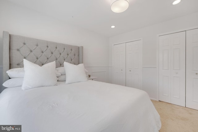 bedroom with light colored carpet and multiple closets