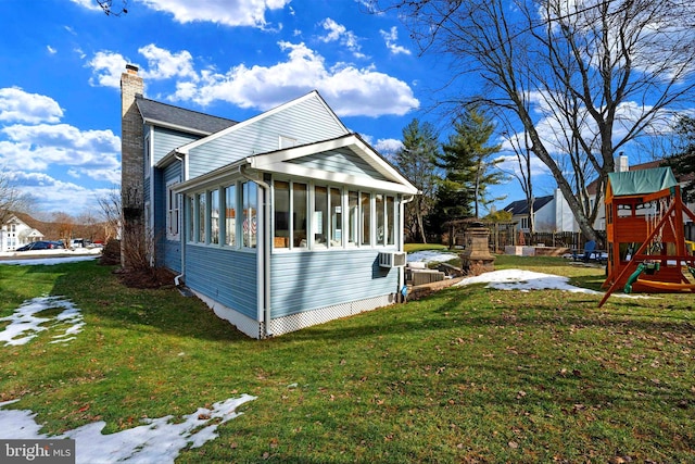 view of home's exterior with a playground, a sunroom, and a yard