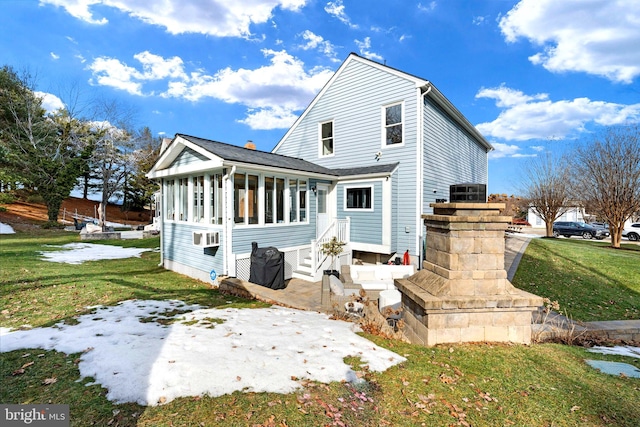 rear view of house featuring cooling unit, a sunroom, a lawn, and a patio area