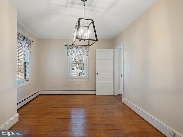 unfurnished dining area featuring wood-type flooring and a baseboard heating unit