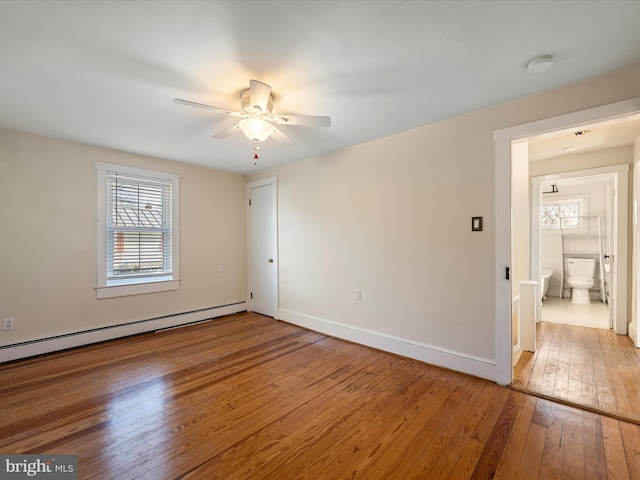 spare room with a baseboard radiator, wood-type flooring, a wealth of natural light, and ceiling fan