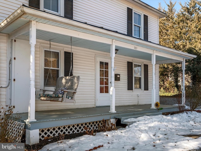 snow covered property entrance with a porch