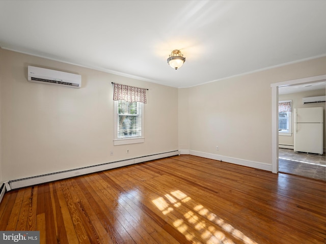 spare room featuring baseboard heating, wood-type flooring, and a wall mounted AC