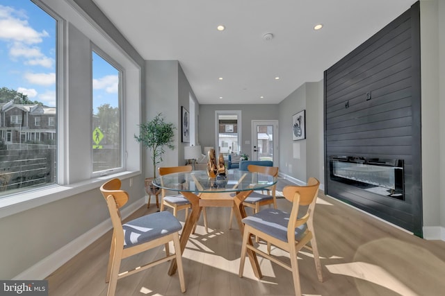 dining space with a fireplace, light hardwood / wood-style flooring, and a healthy amount of sunlight