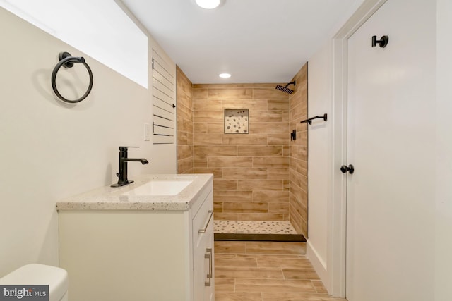 bathroom with vanity, a tile shower, and toilet