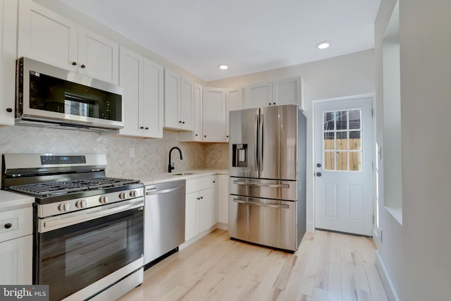 kitchen with white cabinetry, stainless steel appliances, light hardwood / wood-style floors, and sink