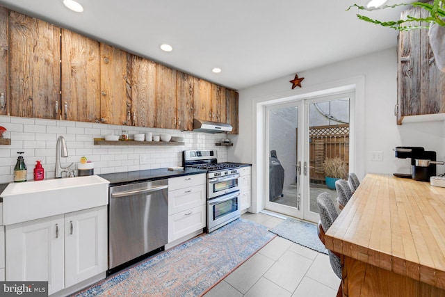 kitchen with appliances with stainless steel finishes, tasteful backsplash, sink, white cabinets, and french doors