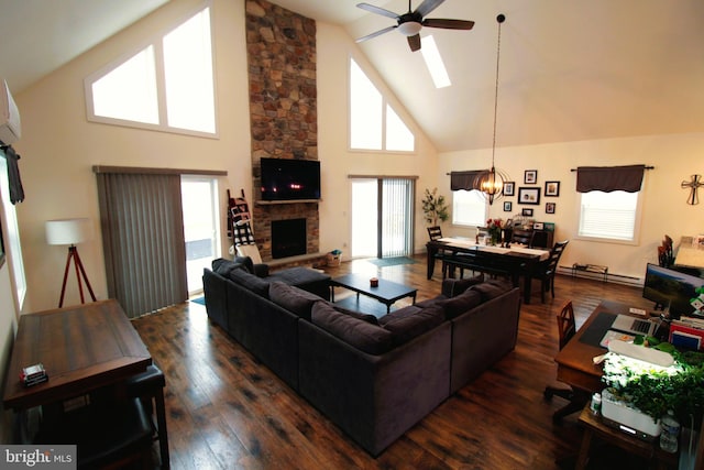 living room featuring dark hardwood / wood-style flooring, a stone fireplace, a healthy amount of sunlight, and high vaulted ceiling