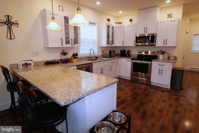 kitchen featuring white cabinetry, hanging light fixtures, stainless steel appliances, and kitchen peninsula