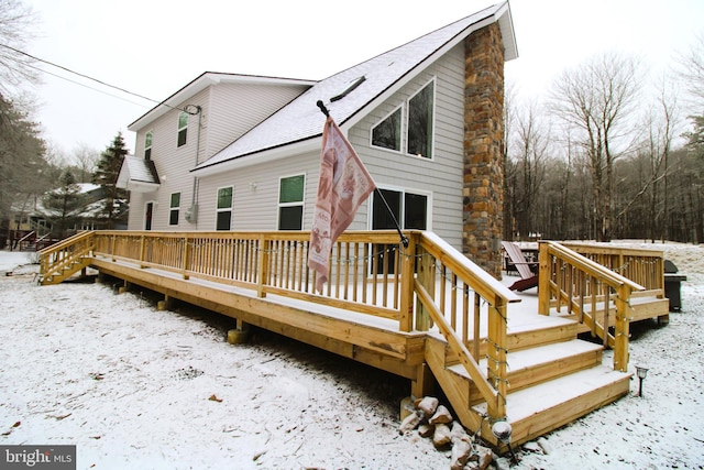 snow covered house with a wooden deck