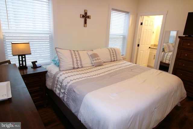 bedroom featuring dark wood-type flooring and ensuite bath