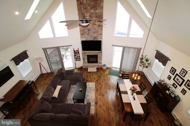 living room with a high ceiling, a stone fireplace, dark hardwood / wood-style floors, and ceiling fan