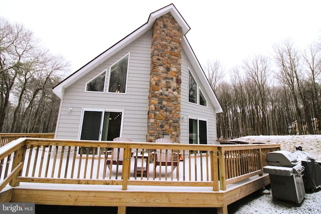 snow covered rear of property featuring a deck