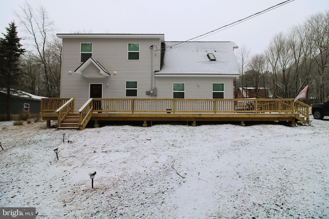 snow covered rear of property featuring a deck