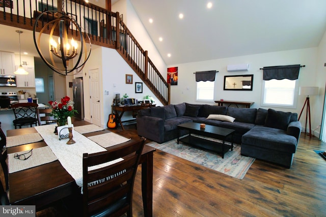 living room with hardwood / wood-style flooring, a towering ceiling, a chandelier, and a wall unit AC