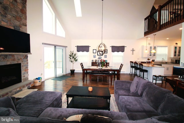 living room featuring hardwood / wood-style flooring, a stone fireplace, a healthy amount of sunlight, and high vaulted ceiling