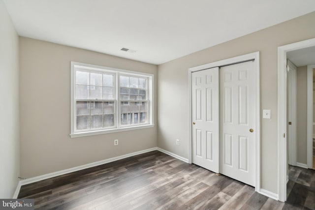 unfurnished bedroom featuring dark wood-type flooring and a closet