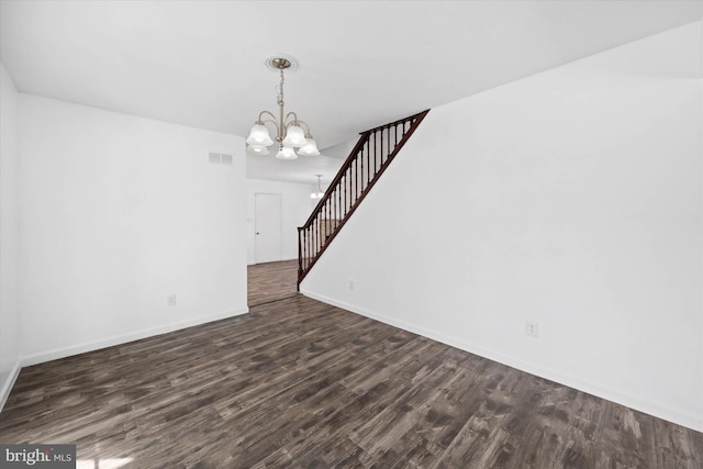 spare room with dark wood-type flooring and a chandelier