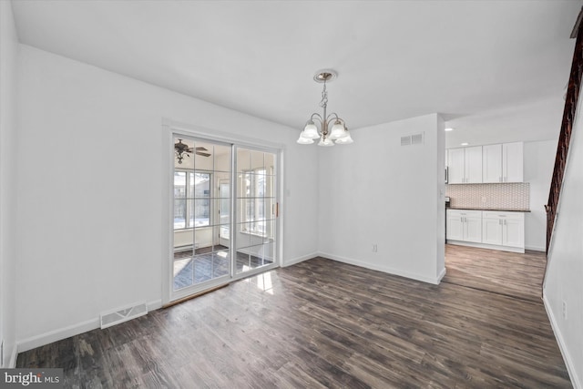 unfurnished dining area featuring a healthy amount of sunlight, an inviting chandelier, and dark hardwood / wood-style floors