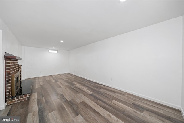 unfurnished living room featuring wood-type flooring and a brick fireplace