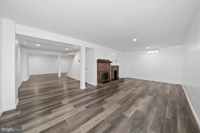 basement with dark hardwood / wood-style flooring and a brick fireplace