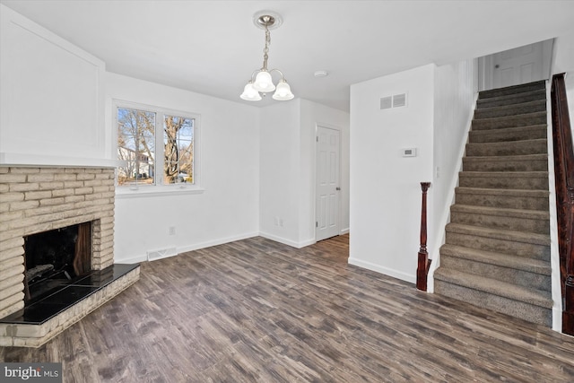 unfurnished living room with dark hardwood / wood-style flooring, a fireplace, and a chandelier