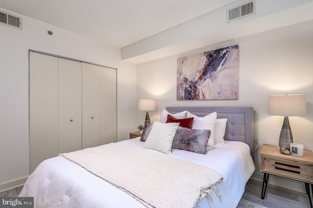 bedroom with hardwood / wood-style flooring, a textured ceiling, and a closet