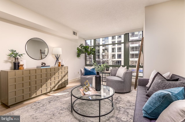 sitting room featuring hardwood / wood-style floors, a wall of windows, and a textured ceiling