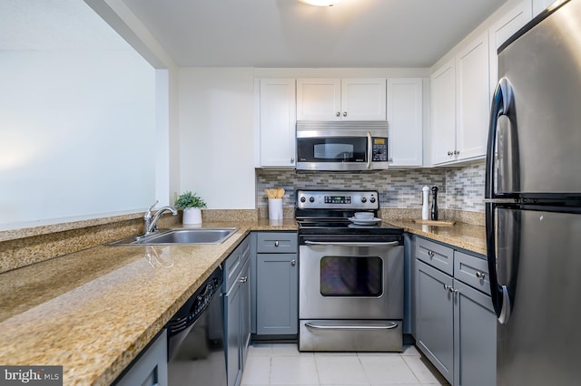 kitchen featuring white cabinetry, sink, decorative backsplash, light tile patterned floors, and stainless steel appliances