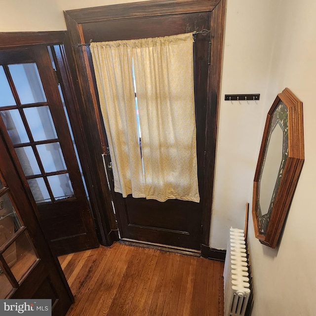 entryway with dark wood-type flooring and radiator heating unit