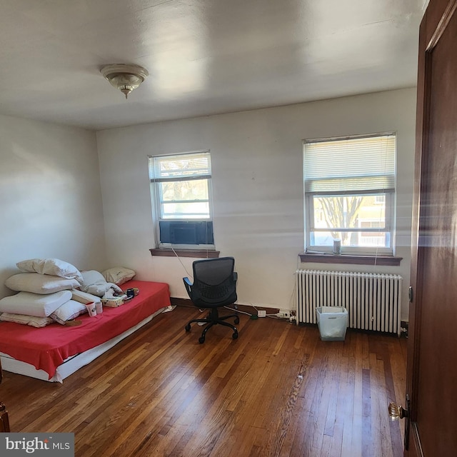 bedroom featuring cooling unit, radiator heating unit, and dark hardwood / wood-style floors