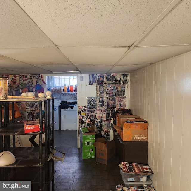 basement with separate washer and dryer, a paneled ceiling, and wooden walls