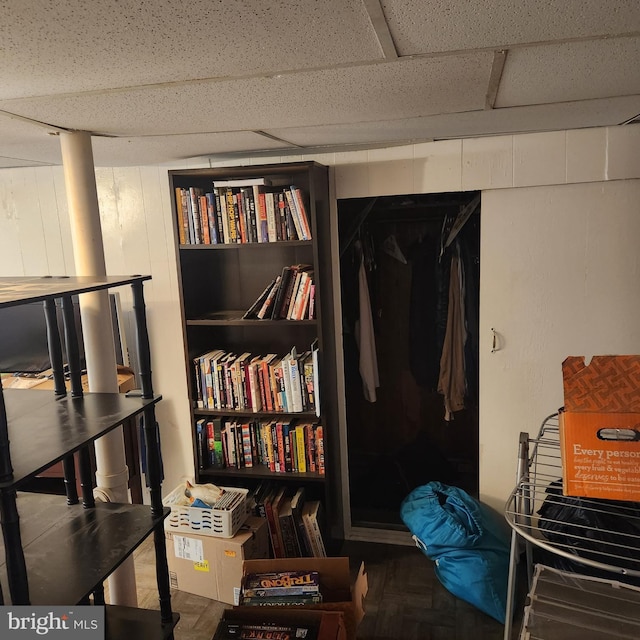 miscellaneous room featuring parquet flooring and a paneled ceiling