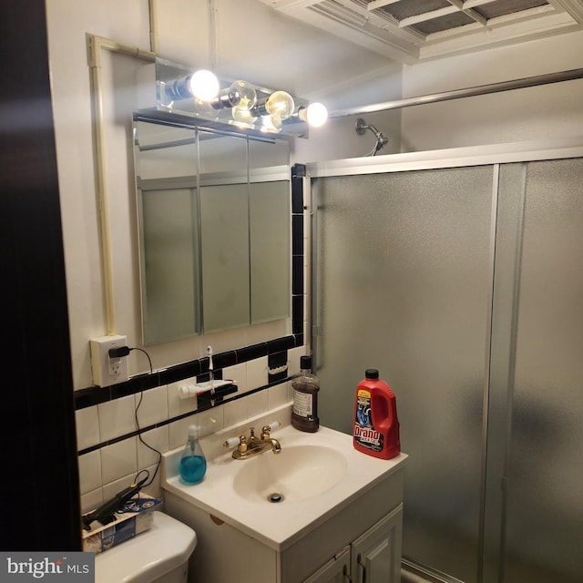 bathroom featuring tasteful backsplash, vanity, toilet, and a shower with door