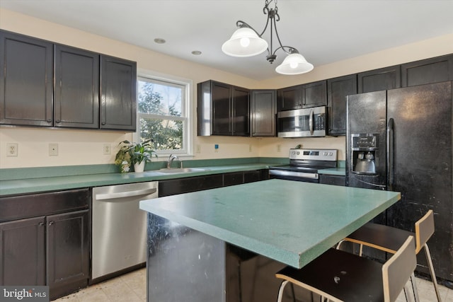 kitchen featuring sink, a breakfast bar area, hanging light fixtures, stainless steel appliances, and a kitchen island