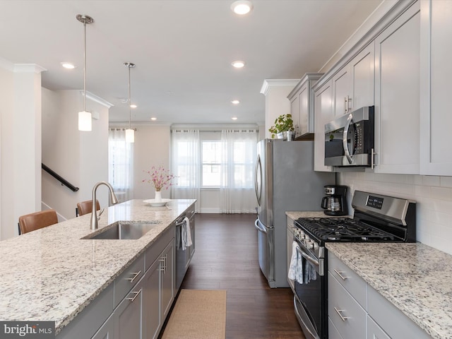 kitchen with sink, gray cabinetry, light stone counters, hanging light fixtures, and appliances with stainless steel finishes