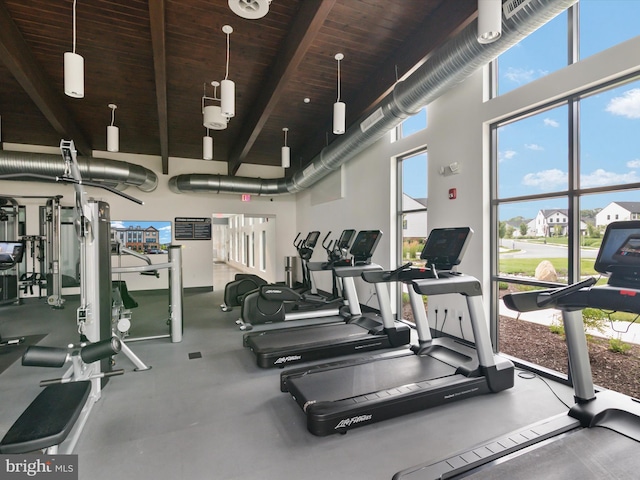 gym featuring a towering ceiling, plenty of natural light, and wooden ceiling