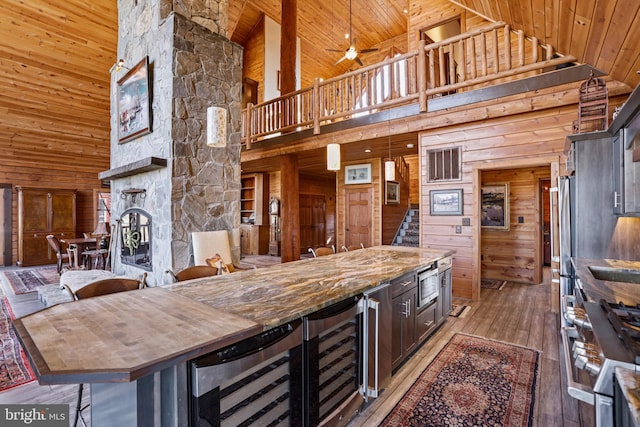 kitchen with appliances with stainless steel finishes, wood walls, beverage cooler, dark wood-type flooring, and wooden ceiling