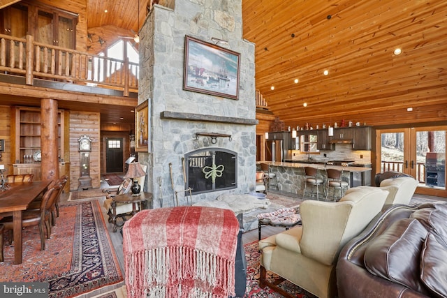 living room featuring high vaulted ceiling, a stone fireplace, wooden ceiling, and wood walls