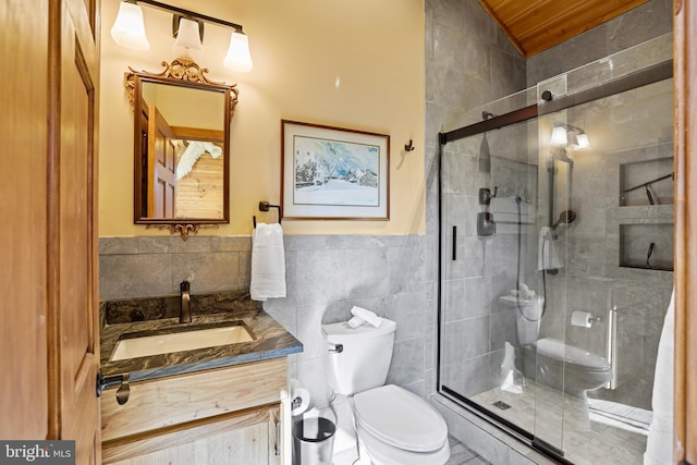 bathroom featuring vanity, toilet, tile walls, and a shower with shower door