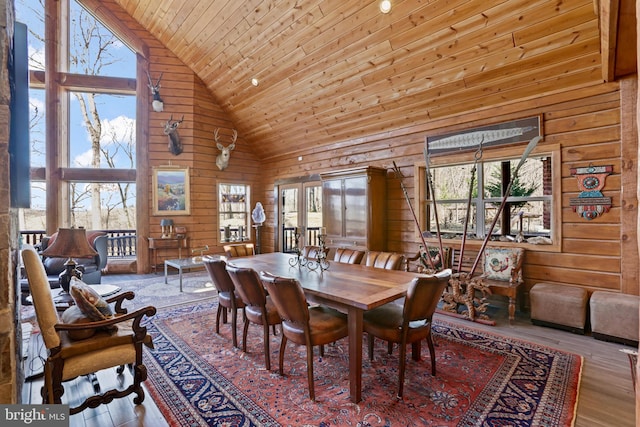 dining room with high vaulted ceiling, wood-type flooring, wooden ceiling, and wood walls