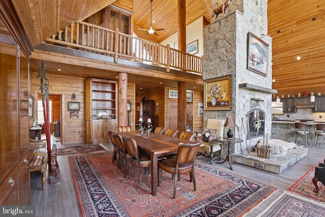 dining room featuring wooden walls, hardwood / wood-style floors, a fireplace, and wood ceiling