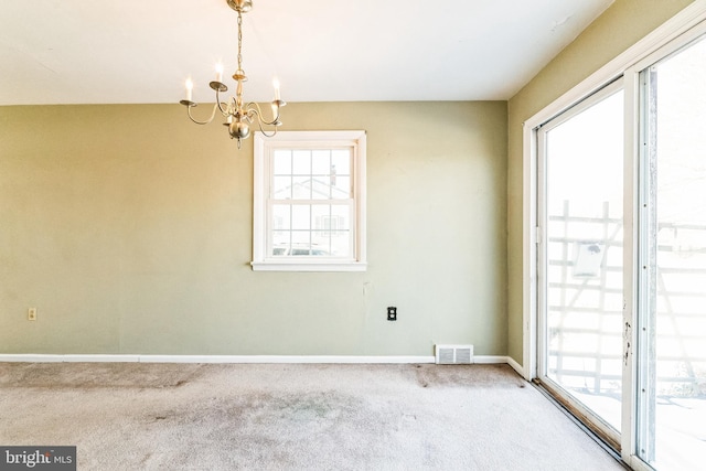 carpeted empty room with a notable chandelier