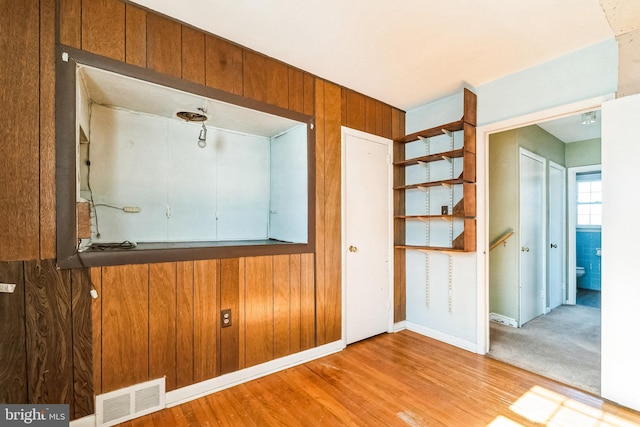 interior space with light hardwood / wood-style flooring and wood walls