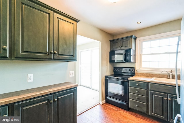 kitchen featuring light wood-type flooring, sink, and black appliances